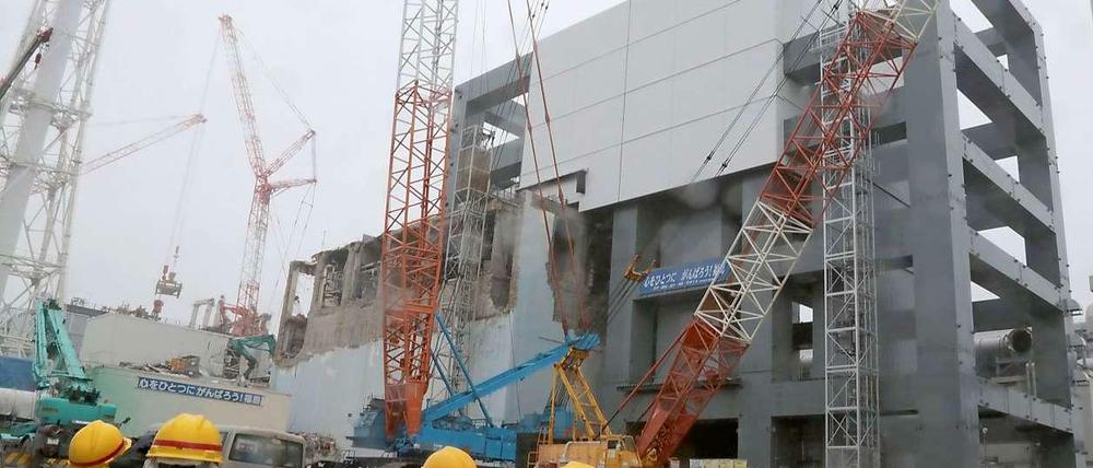 Arbeiter in Schutzanzügen stehen im Juni 2013 vor der Reaktorruine von Fukushima. Bei der Katastrophe starben 2011 über 20.000 Menschen.