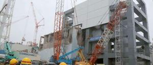 Arbeiter in Schutzanzügen stehen im Juni 2013 vor der Reaktorruine von Fukushima. Bei der Katastrophe starben 2011 über 20.000 Menschen.