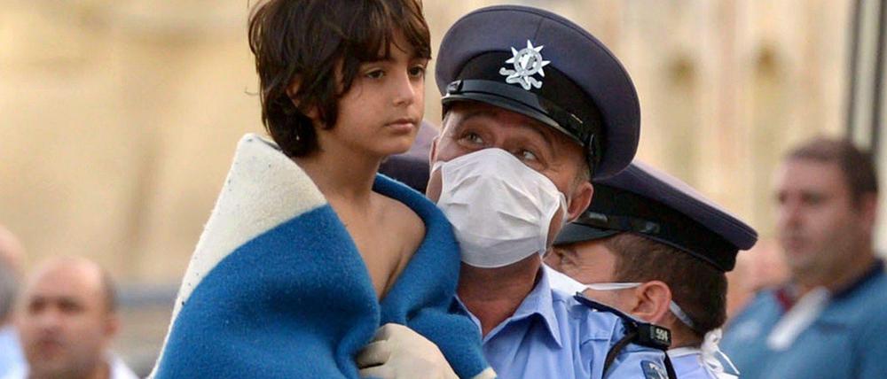 Maltesischer Polizist trägt gerettetes Flüchtlingskind
