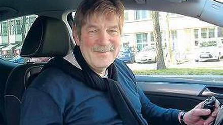 Georg Grasshoff in seinem Fahrschulauto, in der Hand ein spezieller Drehknopf.