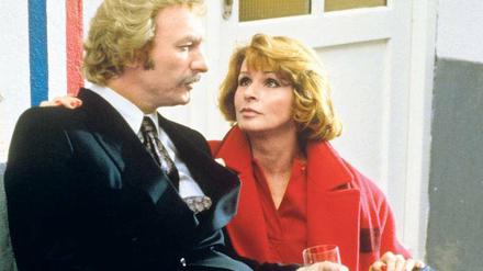 Weltstadt mit Herz. Eine Szene aus der 1986 gestarteten TV-Serie „Kir Royal“ mit Franz Xaver Kroetz (als Reporter Baby Schimmerlos) und Senta Berger (als Mona). Regisseur Helmut Dietl nahm damit auch das Boulevardblatt „AZ“ und das Münchner Lebensgefühl aufs Korn.