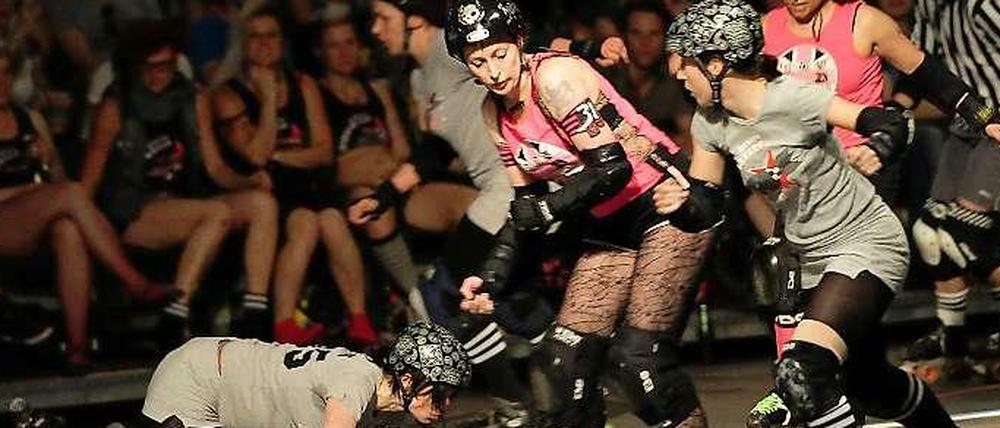 Ab und zu geht es auch mal zu Boden. Die "Berlin Bombshells" (grau) im Wettkampf gegen die Londoner "Brawl Saints" (pink) in einem Roller Derby. 