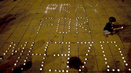 Ein Mädchen zündet eine Kerze für die vermissten Passagiere von Flug MH-370 an.