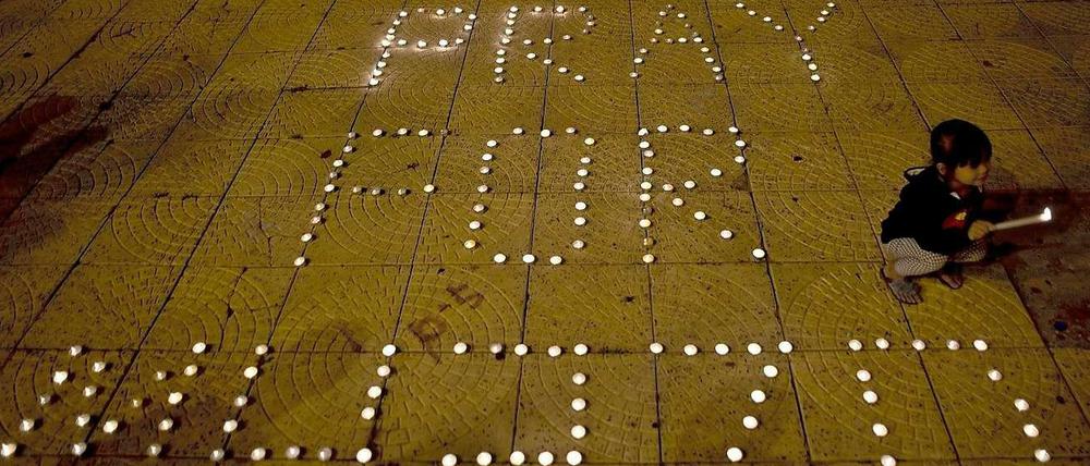 Ein Mädchen zündet eine Kerze für die vermissten Passagiere von Flug MH-370 an.