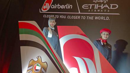 Zwei Stewardessen, eine von Air Berlin, eine von Etihad, stehen hinter zwei Leitwerken mit den Logos der beiden Fluggesellschaften.