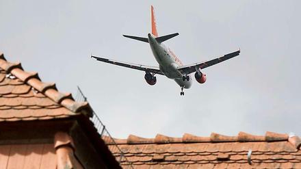 Und sie hören die Motoren. Ein Passagierflugzeug fliegt in Berlin-Bohnsdorf während des Landeanfluges auf den Flughafen Schönefeld (Dahme-Spreewald) dicht über den Hausdächern