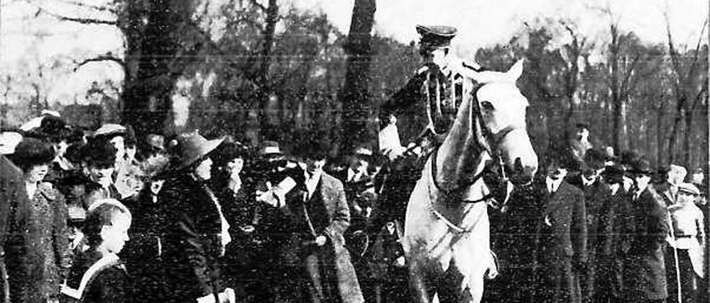 Kronprinz Wilhelm auf einem Pferd im Gespräch mit einem Kindermädchen, umgeben von einer Menschenmenge.