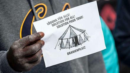 Ein Flüchtling hält ein Protestpapier.