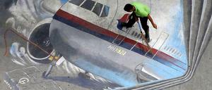 Ein Straßenarbeiter fegt ein Bild von Flug MH 370 in Manila. 