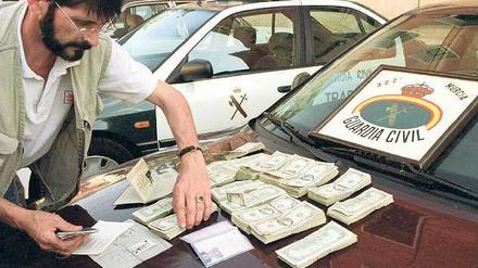 Ein spanischer Beamter prüft Banknoten und Dokumente bei einer früheren Razzia im Fall Reemtsma. 