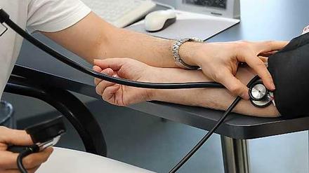 Ein Arzt misst den Blutdruck einer Patientin.