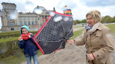 Bei dem Wind, half kein Schirm gegen die Regenschauer. Berlin-Besucher kämpften am Montag am Reichstag mit den Windböen.