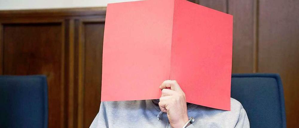 Ein Angeklagter in einem Vergewaltigungsprozess versteckt sich hinter einem Hefter.