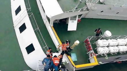 Der Kapitän verlässt das Schiff. Der 69-jährige Lee Jun-seok (dritter von rechts) geht mithilfe von Angehörigen der Wasserpolizei von Bord. 