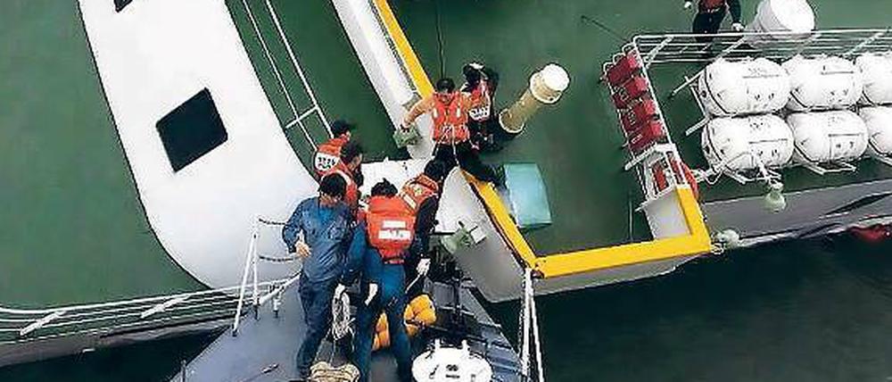 Der Kapitän verlässt das Schiff. Der 69-jährige Lee Jun-seok (dritter von rechts) geht mithilfe von Angehörigen der Wasserpolizei von Bord. 