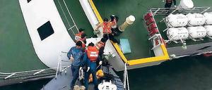Der Kapitän verlässt das Schiff. Der 69-jährige Lee Jun-seok (dritter von rechts) geht mithilfe von Angehörigen der Wasserpolizei von Bord.