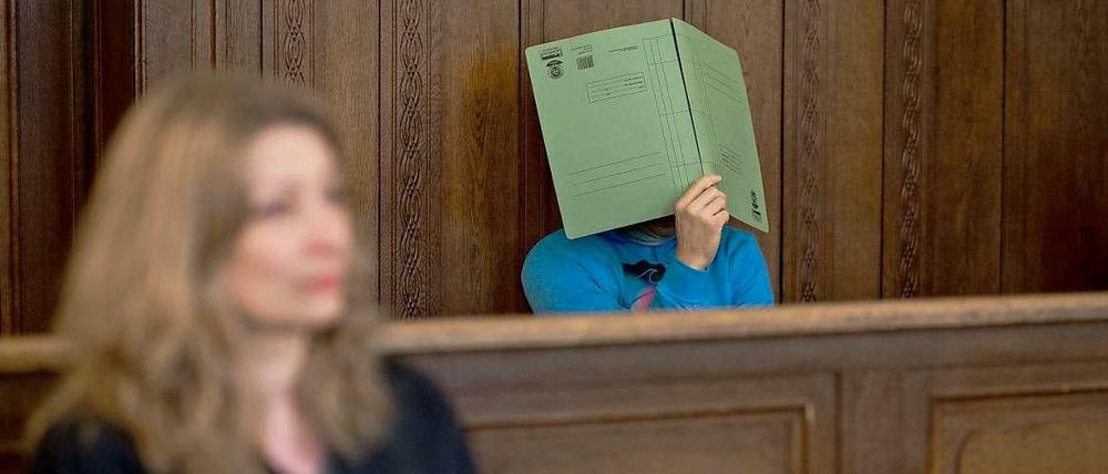 Im Gerichtssaal: Der Angeklagte verdeckt sein Gesicht mit einem Aktenhelfer. Vor ihm, seine Anwältin Julia Hilterscheid.