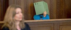 Im Gerichtssaal: Der Angeklagte verdeckt sein Gesicht mit einem Aktenhelfer. Vor ihm, seine Anwältin Julia Hilterscheid.