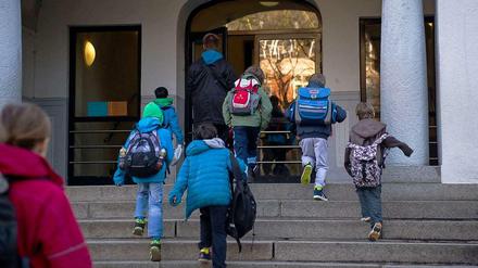 Grundschüler steigen die Treppe zum Eingang ihrer Schule hoch.