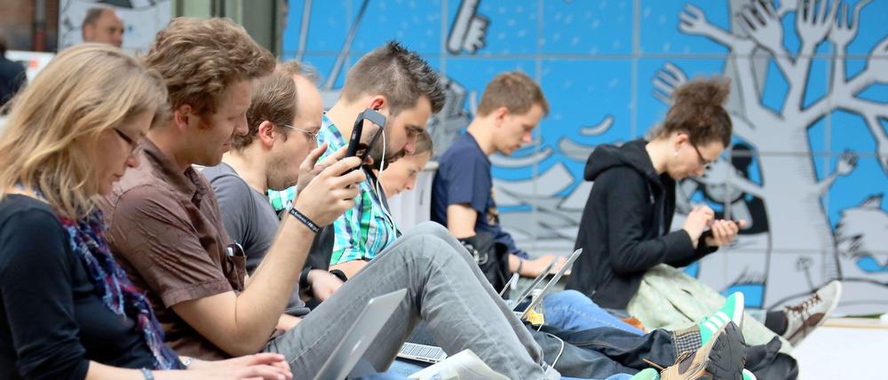 Besucher der Internetkonferenz Re:publica sitzen am 08.05.2013 in Berlin mit ihrem Laptop auf den Knien nebeneinander.