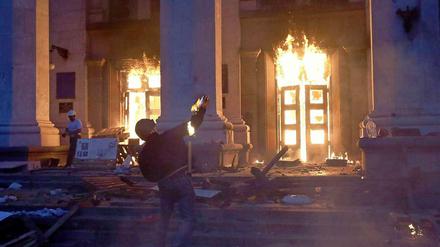 Ein Demonstrant schmeißt einen Brandsatz auf das bereits brennende Gewerkschaftshaus in Odessa.
