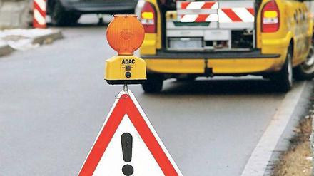 Ein Pennenhelfer des ADAC in Aktion, im Vordergrund und Warnschild, auf dem steht: "Panne, ADAC"