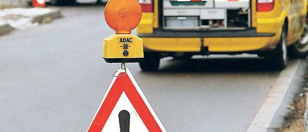 Ein Pennenhelfer des ADAC in Aktion, im Vordergrund und Warnschild, auf dem steht: "Panne, ADAC"
