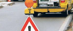 Ein Pennenhelfer des ADAC in Aktion, im Vordergrund und Warnschild, auf dem steht: "Panne, ADAC"