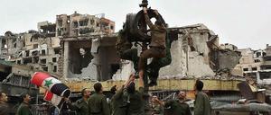 In der zerstörten Stadt Homs hissen Soldaten die syrische Fahne, nachdem die Rebellen abgezogen sind. 