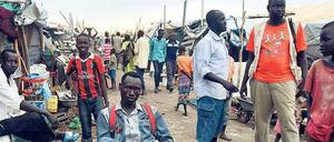 In einem Flüchtlingslager im Südsudan stehen und sitzen Männer und männliche Jugendliche an einem Marktstand.