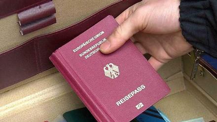 Ein Polizeibeamter zeigt am nach einer Razzia in Berlin-Neukölln einen Koffer mit Reisepässen.