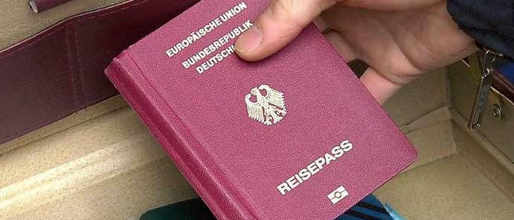 Ein Polizeibeamter zeigt am nach einer Razzia in Berlin-Neukölln einen Koffer mit Reisepässen.