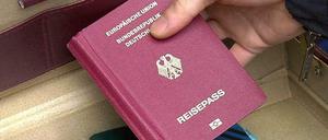 Ein Polizeibeamter zeigt am nach einer Razzia in Berlin-Neukölln einen Koffer mit Reisepässen.