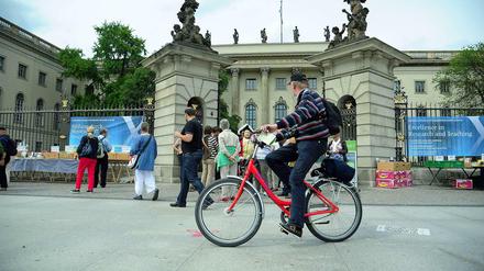 Ein älterer Mann fährt mit seinem Fahrrad auf dem Bürgersteig vor dem Hauptgebäude der Humboldt-Universität vorbei.