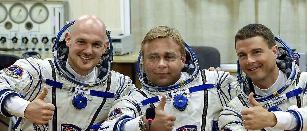 Posing für die Kameras: Vor dem Abflug geben die drei Astronauten noch eine Pressekonferenz - hinter einer Glasscheibe.