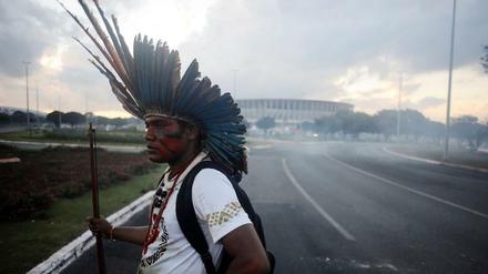 Ein Demonstrant im Federschmuck der Ureinwohner Brasiliens steht vor dem neuen Stadion, dessen Baukosten sich immens gesteigert haben.