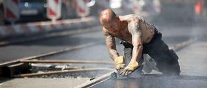 Heiße Angelegenheit: Ein Arbeiter hantiert mit frischem teer an Straßenbahngleisen.