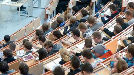 Studierende sitzen in einem Hörsaal und lauschen der Vorlesung eines Professors.