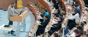 Studierende sitzen in einem Hörsaal und lauschen der Vorlesung eines Professors.