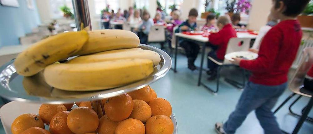 Eine Etagere mit verschiedenen Obstsorten steht auf einem Tisch in der Mensa einer Schule.
