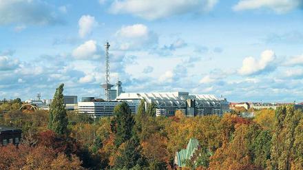 Über den Wipfeln. Das ICC, fotografiert von Halensee aus, mit Blick über die Bäume und die Kapelle des Friedhofs Grunewald. 