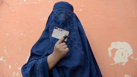 Eine afghanische Wählerin zeigt ihre Wahlkarte vor einem Wahllokal.