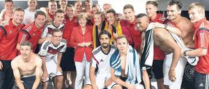 Gruppenbild mit Kanzlerin. Angela Merkel feiert mit der Jogi-Truppe den WM-Einstand. Foto: Guido Bergmann/AFP