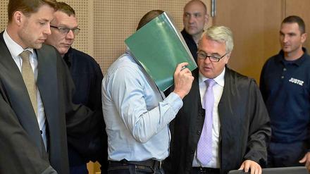 Der Angeklagte Mario K. verdeckt mit einem Hefter sein Gesicht. Das Bild ist von Prozessbeginn Anfang Mai. 