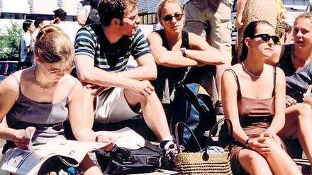 Junge Studierende sitzen vor der Technischen Universität Berlin in der Sonne.