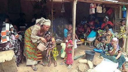 Immer die Hände waschen. Eine Mutter ermutigt ihr Kind in Macenta, Guinea. 