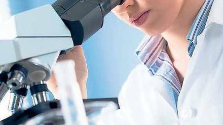 Eine junge Wissenschaftlerin im Labor, die mit einem Mikroskop arbeitet.