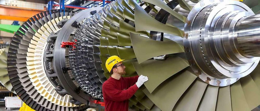 Ein Arbeiter kontrolliert eine Turbine, die bei Siemens in Berlin für ein Düsseldorfer Kraftwerk gefertigt wird.