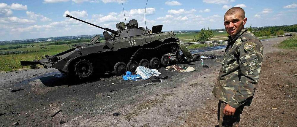 Ein ukrainischer Soldat steht vor einem ausgebrannten Panzerfahrzeug pro-russischer Separatisten. Am Samstag hat die Armee die umkämpfte Stadt Slowiansk nach eigenen Angaben zurückerobert. 