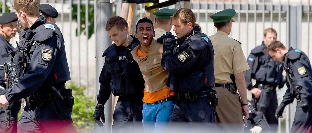 Polizisten führen einen Asylbewerber ab.